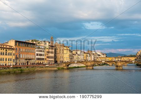 Ponte Santa Trinita or St Trinity Bridge a renaissance bridge in Florence Italy. It is spanning over Arno river with Ponte Vecchio on background. Sunset.