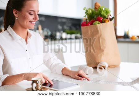 Young woman planning expenses and paying bills on her kitchen