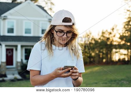 Cute pretty american teenager or hipster millennial woman navigates through her smartphone looks for new technology futuristic application digital native scrolls news feed