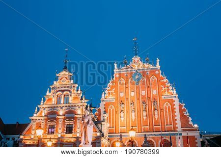 Riga, Latvia. Schwabe House And House Of The Blackheads At Town Hall Square, Ancient Historical Landmark And Popular Touristic Showplace In Summer Evening. Night Illuminations