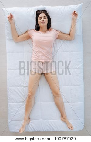 I feel comfortable. Delighted attractive nice woman occupying the whole bed and feeling comfortable while resting at home