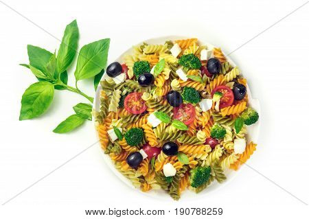 A photo of a plate of pasta salad with basil leaves, shot from above on a white background with a place for text