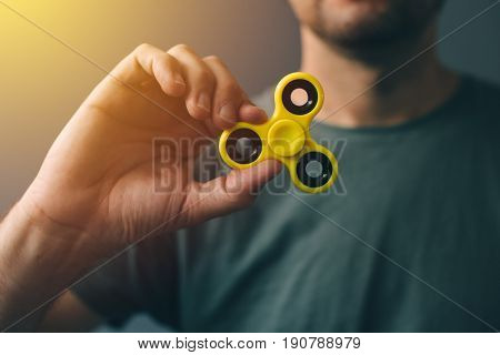 Yellow fidget spinner in male hand selective focus