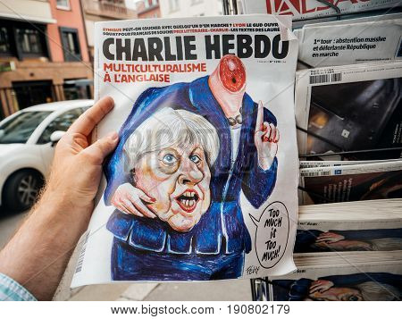 PARIS FRANCE - JUN 12 2017: Man point of view personal perspective buying at press kiosk satire newspaper Charlie Hebdo with Theresa May without head caricature with reactions to United Kingdom general election of 2017 - May fights to remain PM