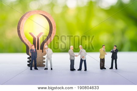 Miniature businessman handshaking with business idea concept using as background commitment agreement investment and partnership concept.