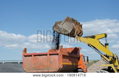 Wheel excavator on gravel pile loading a truck