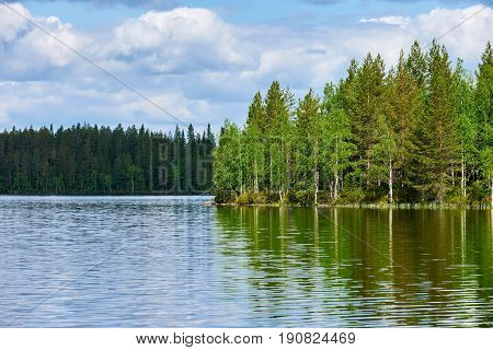 Relaxing Finnish landscape with lake forest trees sky and reflected clouds