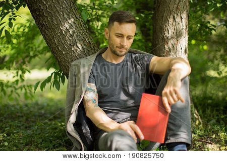 middle aged man rading book in park