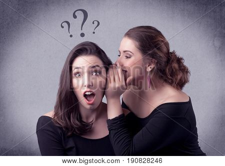 A teenager girl looking confused with drawn question marks above the head, while a girlfriend whispers something in her ear concept.