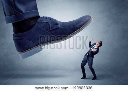 Big foot trying to crush small man who is afraid of that