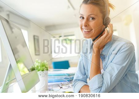 Customer service operator talking on phone in office