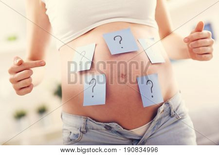 Picture showing pregnant woman with question marks on belly