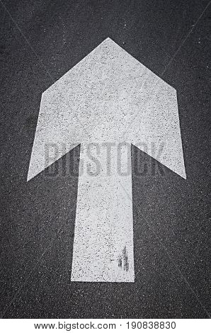 White arrow on the asphalt road top view