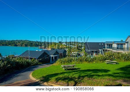 AUCKLAND, NEW ZEALAND- MAY 12, 2017: Gorgeous town in Waiheke island, tourists enjoying the view from the shops to the beach, the tourist destination near Auckland, New Zealand.
