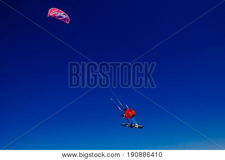 Snowboarder with a kite on fresh snow in the winter in the tundra of Russia against a clear blue sky. Teriberka Kola Peninsula Russia. Concept of winter sports snowkite.