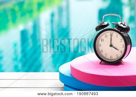 Swimming Times, Retro Black Bell Clock Time At 4 O'clock At Swimming Pool Blur Background.
