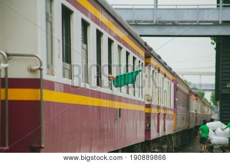 trainman show green flag as sign to driver when safe and ready for train to departure in Thailand.