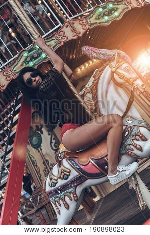 Merry-go-round fun. Attractive young mixed raced woman in red bikini riding merry-go-round