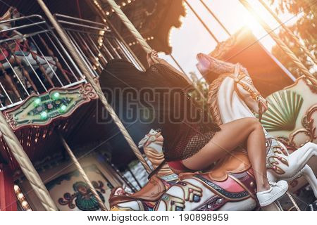 Merry-go-round fun. Rear view of beautiful young woman in red bikini riding merry-go-round