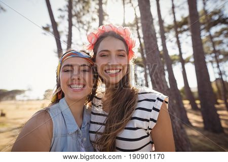Portrait of cheerful friends standing on field at forest