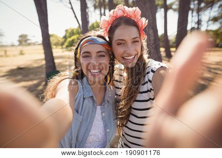 Portrait of smiling friends standing on field at forest