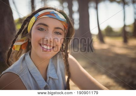 Portrait of woman sitting on field while camping at forest