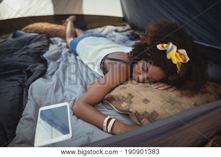 High angle view of young woman sleeping by tablet in tent