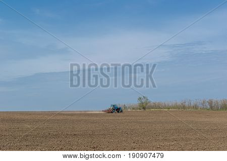 An old tractor in the field plows the land. Spring landscape of a countryside a farm.