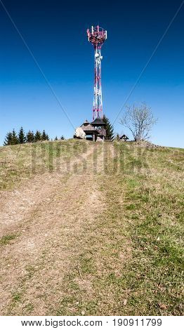 Kamenite hill in Javorniky mountains in Kysuce region in Slovakia with communication tower small wooden view tower big stone mountain meadow with pathway and clear sky