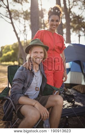 Portrait of smling couple by tent at forest