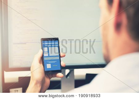 mobile app development - smart phone with application wireframe in programmer hand