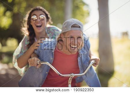 Happy couple riding bicycle against trees at forest