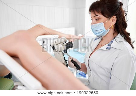 Female gynecologist working at the hospital examining her patient on a gynecological chair profession job occupation medicine clinical healthcare feminine concept.