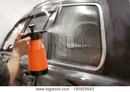 Worker spraying water onto car window prior to tinting