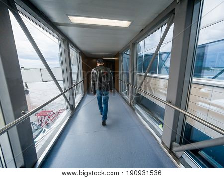 Man boarding in airport gate or jet bridge or jetway or airbridge to a plane, tunel vision, perspective