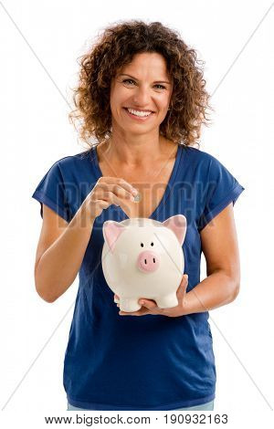 Portrait of a happy middle aged woman puting some money on a Piggybank