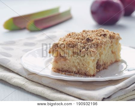 Coffee cake decorated with streusel and fresh rhubarb stems. Homemade apple pudding. Selective focus.
