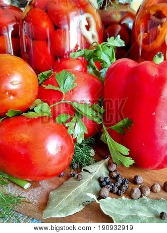 Home canning for the winter glass jars with red tomatoes and greens