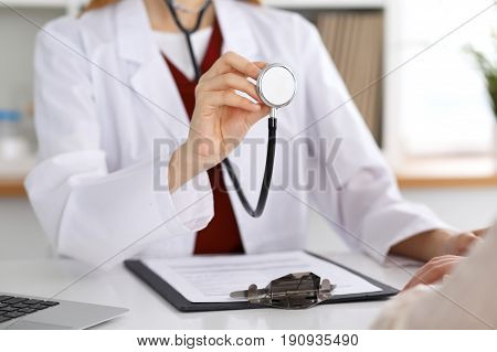 Unknown female doctor with a stethoscope in the hands. Physician is redy to exemine a patient. Medicine and health care conept