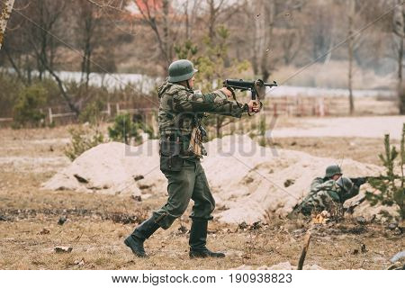 Gomel, Belarus - November 26, 2016: Re-enactor Dressed As German Wehrmacht Infantry Soldier In World War II Open Fire From Sub-machine Gun During Historical Reenactment.
