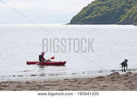 Oxwich beach, Wales, 14-08-2010: An old man sitting in a bright red kayak in Wales.