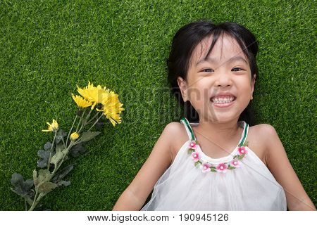 Asian Chinese Little Girl Lying On The Grass With Flowers