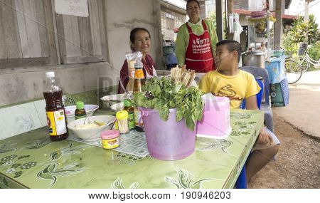 Chang Mai, Thailand - May 28, 2011: Three people sitting at a table and smiling for the camera in Chiang Mai.