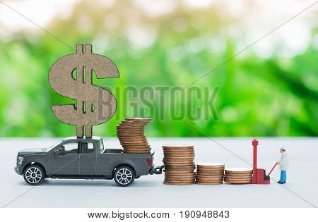 Miniature truck with dollar sign carrying stack of coins worker loading stack of coins using as a business concept.