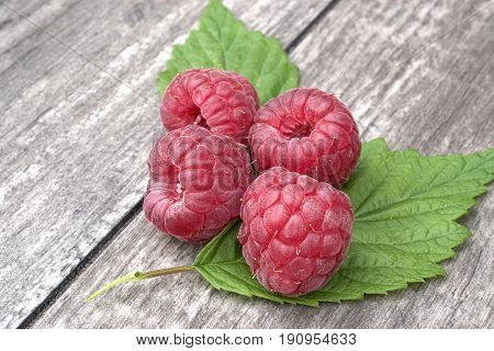 Ripe and fresh raspberries on wooden background.