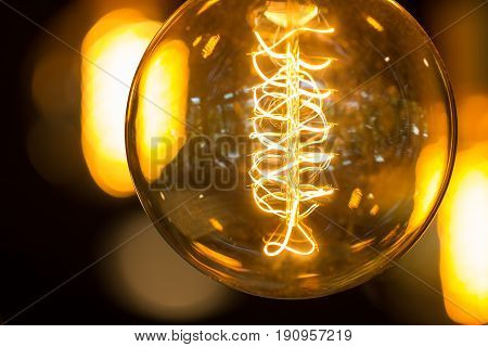 Close up a light bulb decoration on ceiling with blur bokeh group of light on background lighting in the dark. vintage style.