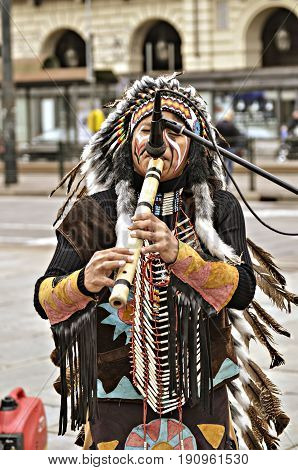 Turin, Italy - April 27, 2013: Red indian in traditional costume plays in the center of Turin, Italy. Street performance of a group of Native Americans with sounds and traditional dancing.