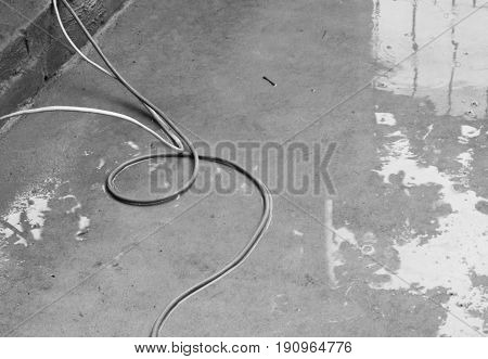 BLACK AND WHITE PHOTO OF WIRE ON WET CONCRETE GROUND
