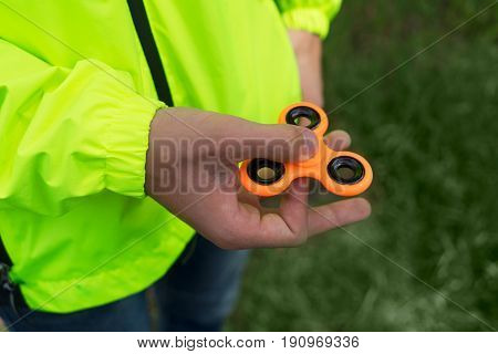 trendy fidget spinner - someone holding orange fidget spinner in hand, close up view