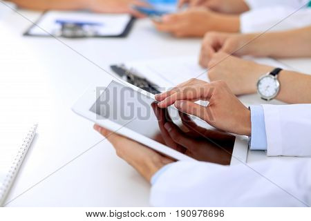 Group of doctors at medical meeting. Close up of physician using tablet computer
